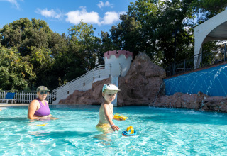 Kvinde og barn leger i pool med legetøjsbåde i Sandaya Le Pianacce feriepark i Toscana, Italien.