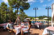 Huéspedes disfrutan de una comida al aire libre junto a la piscina en Sandaya Le Pianacce, Toscana.