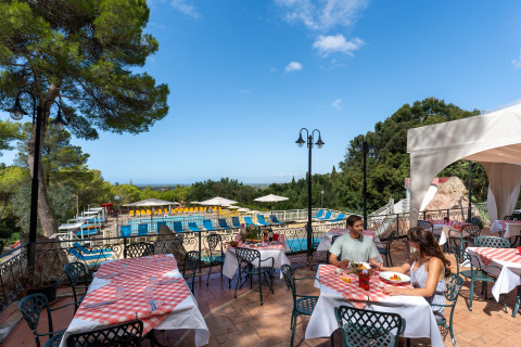 Udendørs restaurantområde ved Sandaya Le Pianacce feriepark i Toscana, Italien, med udsigt til pool.