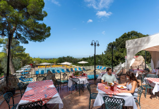 Udendørs restaurantområde ved Sandaya Le Pianacce feriepark i Toscana, Italien, med udsigt til pool.