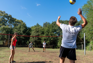 Gæster spiller volleyball udendørs på Sandaya Le Pianacce feriepark i Toscana, Italien, en solrig dag.