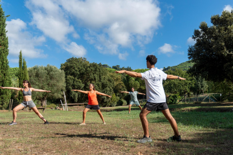 Gruppe mennesker laver udendørs træning i naturen på Sandaya Le Pianacce feriepark i Toscana, Italien.