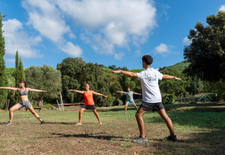 Gruppe mennesker laver udendørs træning i naturen på Sandaya Le Pianacce feriepark i Toscana, Italien.