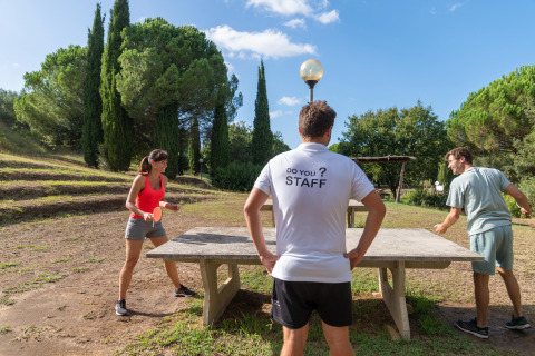 Tre personer spiller bordtennis udendørs på Sandaya Le Pianacce feriepark i Toscana, Italien.