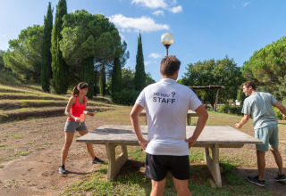 Tre personer spiller bordtennis udendørs på Sandaya Le Pianacce feriepark i Toscana, Italien.
