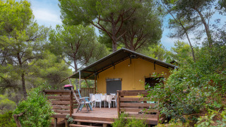 Safari-tent Lodge Country Kids midden in het bos, met houten terras en buiten zitplaatsen onder de bomen.