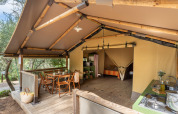 Safari telt med udendørs spiseområde, træmøbler og køkkenplads på Sandaya Le Pianacce, Italien.