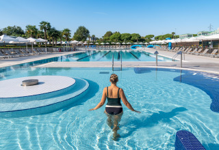 Donna entra nella piscina del villaggio turistico Sandaya Europa Village in Veneto, Italia, tra lettini e ombrelloni.