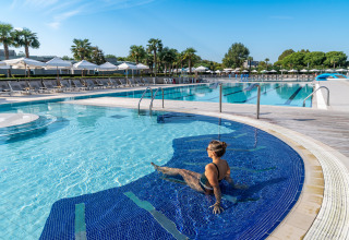 Mujer relajándose en la piscina de Sandaya Europa Village, un parque vacacional en Véneto, Italia, bajo el sol.