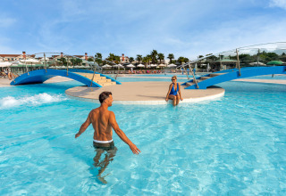 Deux personnes profitent de la piscine au Sandaya Europa Village, un parc de vacances en Vénétie, Italie, sous le soleil.