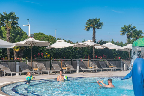 Famille profite d'une journée ensoleillée à la piscine sous des parasols au Sandaya Europa Village, Vénétie, Italie.