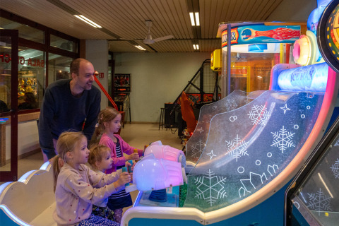 Kinderen en volwassene spelen een arcadespel in Sandaya Europa Village, Veneto, Italië tijdens vakantie.