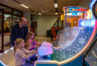Kinderen en volwassene spelen een arcadespel in Sandaya Europa Village, Veneto, Italië tijdens vakantie.