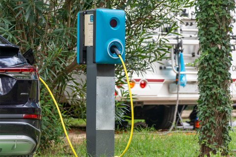 Coche eléctrico cargando en una estación rodeada de vegetación en Sandaya Europa Village, Véneto, Italia.