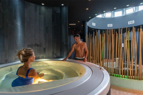 Dos personas disfrutan de un moderno spa con jacuzzi en el Sandaya Europa Village en Véneto, Italia.