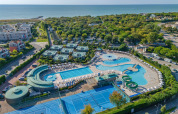 Vue aérienne du village vacances Sandaya Europa Village en Vénétie, Italie, avec piscines, tennis et vue sur mer.