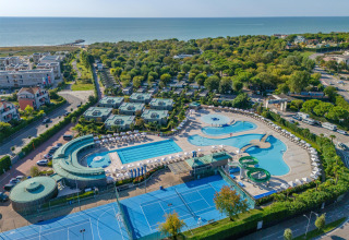 Luchtfoto van Sandaya Europa Village vakantiepark in Veneto, Italië, met zwembad, tennisbanen en zeezicht.