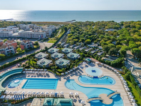 Vista aerea del villaggio turistico Sandaya Europa Village in Veneto, Italia, con piscine e vista mare.