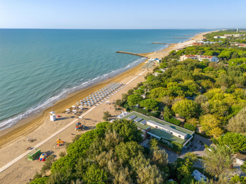 Aerial view of Sandaya Europa Village holiday park in Veneto, Italy, with beach, umbrellas and greenery.