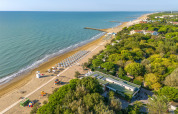 Vista aerea del villaggio vacanze Sandaya Europa Village in Veneto, Italia, con spiaggia e ombrelloni.