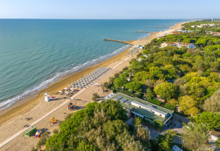 Luftfoto af Sandaya Europa Village i Veneto, Italien, med strand, parasoller og grønt område.