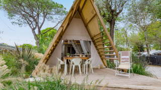 Safari tent Lodge Luxury met A-frame, houten terras en tuinmeubilair omgeven door groen.