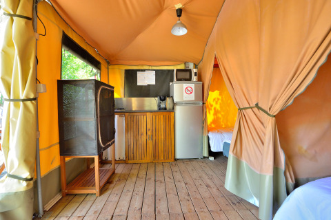 Interior of a safari tent with kitchenette and wooden floor at Campsite Seasonova Etang de la Vallée, France.