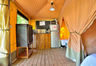Interno di una tenda safari con angolo cottura e pavimento in legno al Campsite Seasonova Etang de la Vallée, Francia.