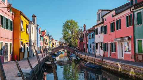 Kleurrijke huizen aan een kanaal in de buurt van Cavallino Treporti, Veneto, Italië, met boten en brug.