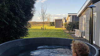 Person entspannt in einem Außenwhirlpool bei der Lodge Ravenbosch im Resort Mooi Bemelen, Niederlande.