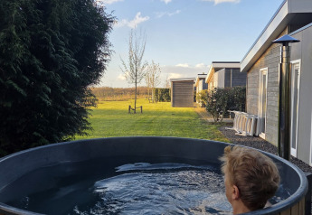 En person slapper af i et udendørs vildmarksbad ved en træhytte på Resort Mooi Bemelen, Ravenbosch, Holland.