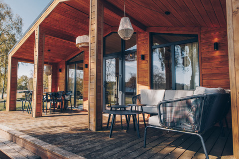 Moderne Holzterrasse mit Sitzgelegenheiten am The Beach House in der Wilsumer Berge Lodge, Deutschland.