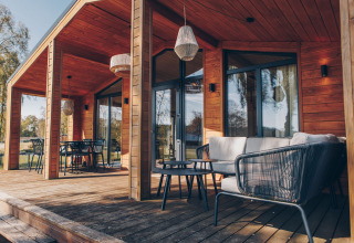 Moderne Holzterrasse mit Sitzgelegenheiten am The Beach House in der Wilsumer Berge Lodge, Deutschland.