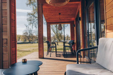 Véranda en bois accueillante au Beach House de Wilsumer Berge en Allemagne, avec sièges et vue sur la nature