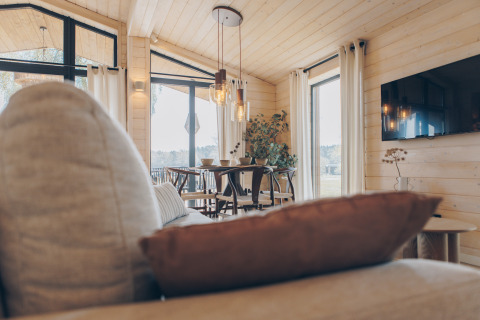 Gemütliches Wohnzimmer im The Beach House Wilsumer Berge, Deutschland, mit heller Holzeinrichtung und Panoramafenstern.