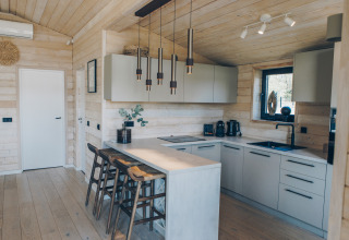 Intérieur de cuisine moderne en bois au Beach House de Wilsumer Berge, Allemagne, avec suspensions et ilot central.