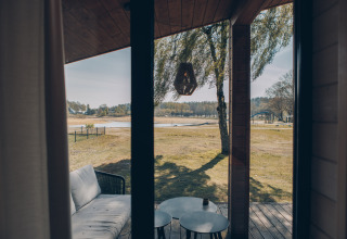 Blick aus dem Beach House in Wilsumer Berge, Deutschland, mit Terrasse, Sofa und Landschaft im Hintergrund.
