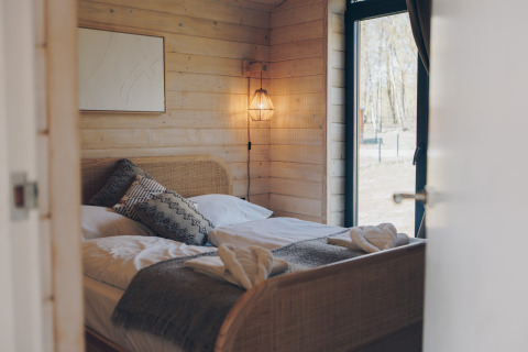 Chambre chaleureuse du Beach House à Wilsumer Berge, Allemagne, avec murs en bois et grande fenêtre.