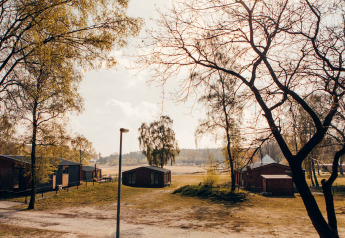 Vue sur le lodge Hill Side Scandi à Wilsumer Berge, Allemagne, avec chalets et arbres sous la lumière matinale.
