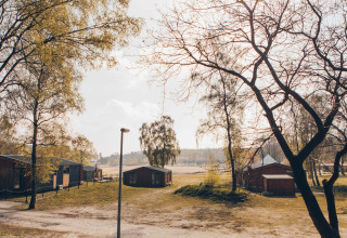 Uitzicht op Hill Side Scandi-lodge bij Wilsumer Berge in Duitsland met huisjes en bomen in het zonlicht.