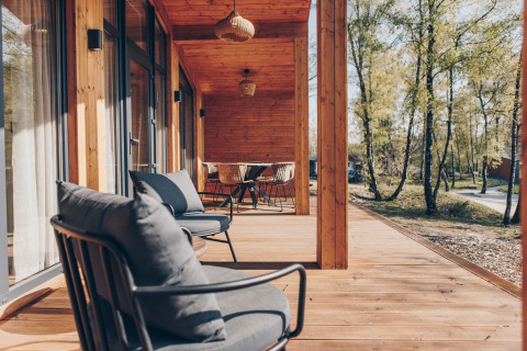 Houten terras met zitjes bij Hill Side Scandi lodge in Wilsumer Berge, Duitsland, omgeven door bomen.