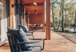 Houten terras met zitjes bij Hill Side Scandi lodge in Wilsumer Berge, Duitsland, omgeven door bomen.