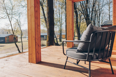 Uitzicht vanaf een houten terras met moderne stoel bij Hill Side Scandi lodge, Wilsumer Berge, Duitsland in de lente.