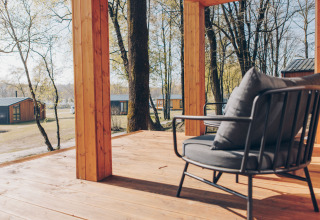 Uitzicht vanaf een houten terras met moderne stoel bij Hill Side Scandi lodge, Wilsumer Berge, Duitsland in de lente.