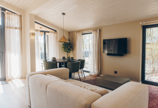 Moderne woonkamer in Hill Side Scandi lodge, Wilsumer Berge, Duitsland, met grote ramen en natuurlijk licht.