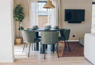 Moderne eethoek in de Hill Side Scandi lodge bij Wilsumer Berge, Duitsland, met vier stoelen en servies.