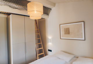 Moderne slaapkamer in Hill Side Scandi, Wilsumer Berge, Duitsland, met ladder en wanddecoratie.