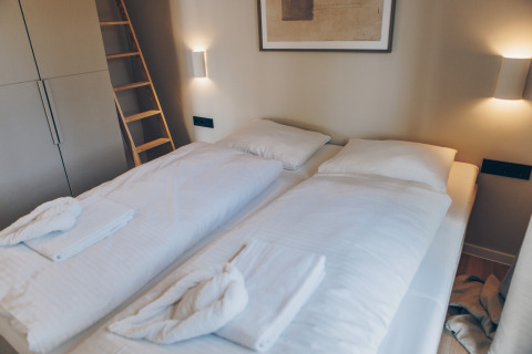 Moderne slaapkamer in Hill Side Scandi lodge in Wilsumer Berge, Duitsland, met twee eenpersoonsbedden.