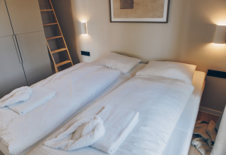 Moderne slaapkamer in Hill Side Scandi lodge in Wilsumer Berge, Duitsland, met twee eenpersoonsbedden.