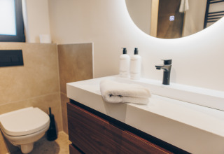 Moderne badkamer in Hill Side Scandi, Wilsumer Berge, Duitsland met spiegel, wastafel en toilet.